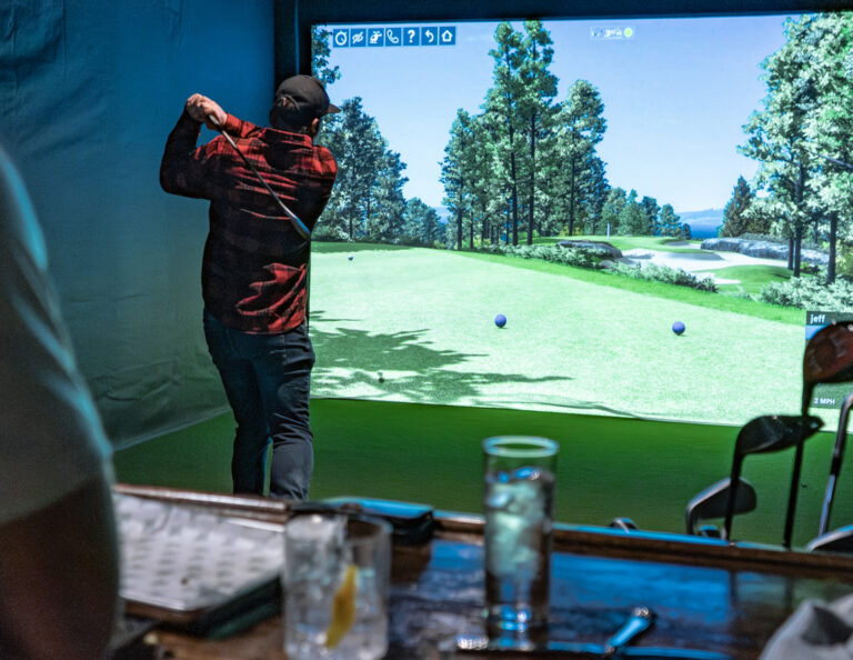 Guy hitting a golf ball on the golf simulator at Birdie Bros